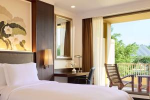 a bedroom with a bed and a desk and a balcony at Dusit Thani Pattaya in North Pattaya