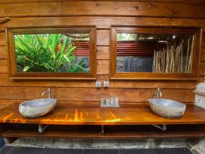 two sinks on a wooden counter with two mirrors at Cocochill Surfhouse in Biha