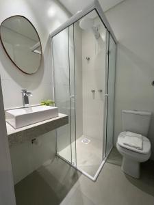 a bathroom with a sink and a mirror and a toilet at Apto Home & Club em Capão da Canoa in Capão da Canoa