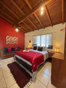 ein Schlafzimmer mit einem großen Bett mit einer roten Wand in der Unterkunft Pousada VistaCalma in Praia do Rosa