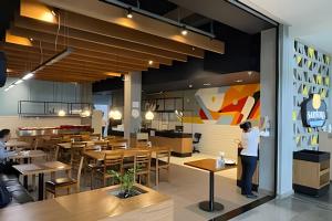 a person standing in a restaurant with tables and chairs at iFlat brookfield Towers BTLX2817 Jardim Goiás in Goiânia