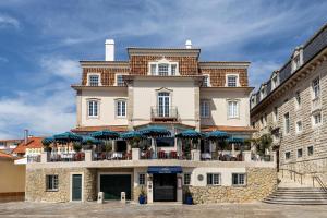a large building with a balcony with blue umbrellas at Villa Cascais Boutique Hotel in Cascais