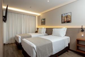 a hotel room with two beds and a window at Hotel Roochelle Convention By Nobile in Curitiba