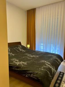 a bedroom with a bed with black sheets and a window at Kleon Apartament in Pristina
