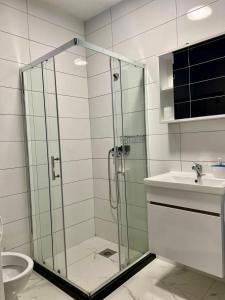 a bathroom with a glass shower and a sink at Kleon Apartament in Pristina