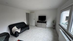 LangenlonsheimにあるBungalow im Parkのリビングルーム(黒い革張りのソファ、テレビ付)