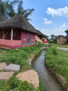 une maison rouge avec un ruisseau devant dans l'établissement Greenland Resort and Family Restaurant, à Munirābād