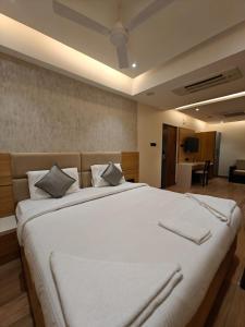 a bedroom with a large bed with white sheets and pillows at Hotel Isha Inn in Guntūr