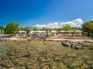 a body of water with rocks and umbrellas at Eurocamp Tents at Campsite Polari in Rovinj