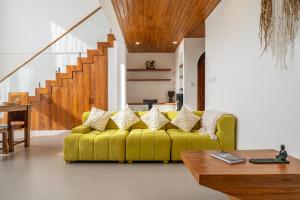 a yellow couch in a living room with stairs at Darina Villa - Private Rooftop Escape with Pool Close to Beach in Badung