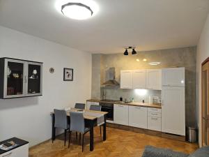 a kitchen with white cabinets and a table and chairs at Apartman Judita in Zagreb