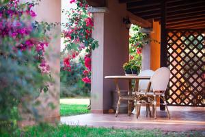 two chairs and a table on a porch with flowers at Residence with swimming-pool in Campulongu just 600 mt from the sea in Campu Longu +26 photos
