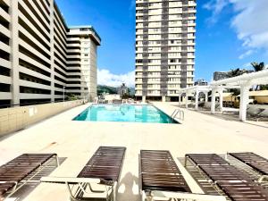 a swimming pool with lounge chairs and a building at Ocean Canal Mountain View Steps from Waikiki Beach 6person in Honolulu