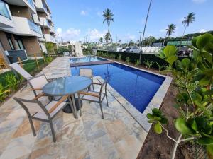 a patio with a table and chairs next to a swimming pool at Flat em Muro Alto - Porto de Galinhas - MAKIA B117 - By Anfitrião Legal in Porto De Galinhas