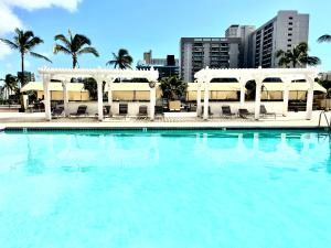 a large swimming pool with white gazebos and palm trees at Ocean Canal Mountain View Steps from Waikiki Beach 6person in Honolulu