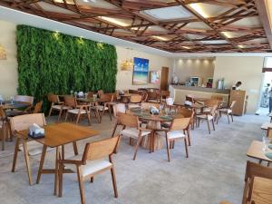 a restaurant with tables and chairs and a green wall at Flat em Muro Alto - Porto de Galinhas - MAKIA B117 - By Anfitrião Legal in Porto De Galinhas
