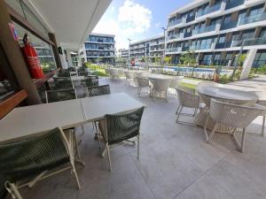 a patio with tables and chairs and a building at Flat em Muro Alto - Porto de Galinhas - MAKIA B117 - By Anfitrião Legal in Porto De Galinhas