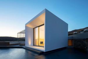 a white house with a large window on a roof at PNOĒS Tinos in Tinos