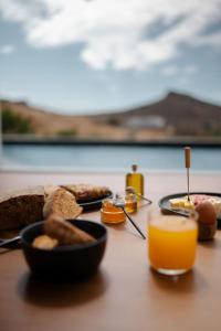 a table topped with plates of food and orange juice at PNOĒS Tinos in Tinos Town +38 photos