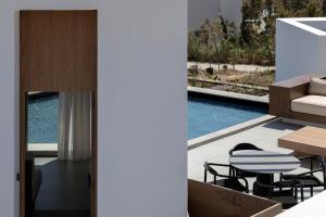 a house with a balcony with a table and chairs at PNOĒS Tinos in Tinos