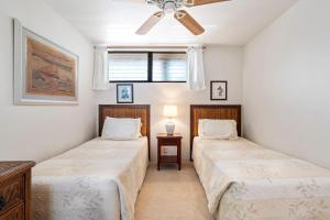 two beds in a bedroom with a ceiling fan at Sea Village 4-205 in Kailua-Kona +30 photos