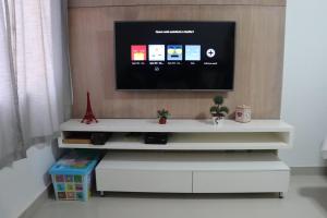 a tv sitting on top of a white entertainment center at CONFORTO IMBATIVEL - 25 metros do MAR - 2 Quartos com AR CONDICIONADOS SPLIT, Air Fryer, WI-FI, Disney Plus, Star Plus, HBO Max, Guarda Sol, Cadeiras de Praia e Caixa Térmica - 8 pessoas com Muito Conforto - Melhor Localização! in Guarapari +21 photos