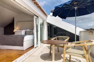a balcony with a bed and a table and an umbrella at Villa Cascais Boutique Hotel in Cascais