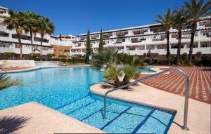 a swimming pool with palm trees and a building at Spirit of 66 in Mojácar
