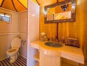 a bathroom with a toilet and a sink with a mirror at Sunshine luxury tent in Merzouga +34 photos
