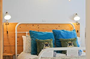 a bed with blue pillows and a wooden headboard at 1 Apse Castle Cottage - Chocolate Box Cottage, Pet-Friendly 16th Century Cottage, surrounded by Ancient Woodland in Shanklin in Shanklin