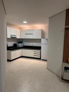 una cocina con armarios blancos y electrodomésticos blancos en Top beach flat, en Porto Seguro