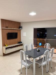 Un comedor con mesa y sillas y un televisor. en Top beach flat, en Porto Seguro