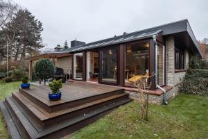 a house with a wooden deck in the yard at Ferienhaus Timm in Meldorf