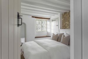 une chambre blanche avec un lit blanc et une fenêtre dans l'établissement Banksia Cottage, à Enstone