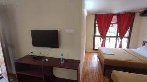 a hotel room with a bed and a desk with a television at Auro Coastal Haven in Pondicherry