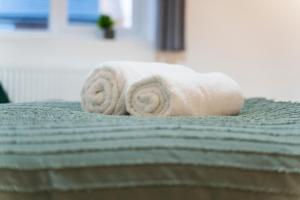 a roll of white towels sitting on top of a bed at Rubys Retreat-4 Bed- Contractor Disc- WiFi in Leavesden Green +45 photos