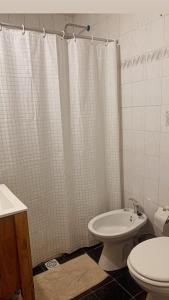 a bathroom with a toilet and a shower curtain at Bella Casa La Costa in Santa Teresita +7 photos