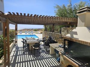 a patio with a table and chairs and a swimming pool at Villa Danae in Makry Gialos
