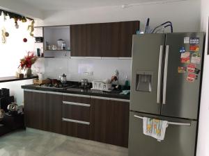 a kitchen with a stainless steel refrigerator and wooden cabinets at Casa Jazmín del Valle, Tranquilidad y Comodidad in Roldanillo