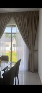 a dining room with a table and chairs and a large window at Homestay Mdm Mai 2 in Masjid Tanah