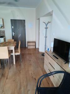 a living room with a television and a dining table at Apartament Perła Bałtyku in Grzybowo