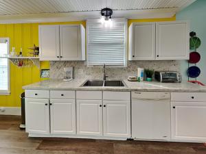 Una cocina con gabinetes blancos y un fregadero. en Seawall Celebration - Up, en Galveston