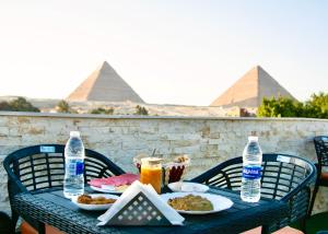 una tavola con cibo e bevande con piramidi sullo sfondo di Keeper Pyramids View INN a Il Cairo