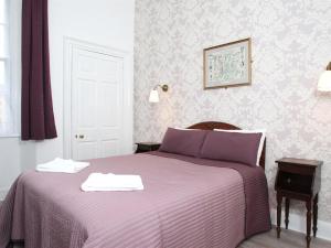 a bedroom with a purple bed with two towels on it at Glasgow city Charlotte service Aparments in Glasgow