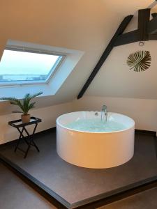 a large bath tub in a room with a window at Les Suites de Bougainville in Concarneau +11 photos