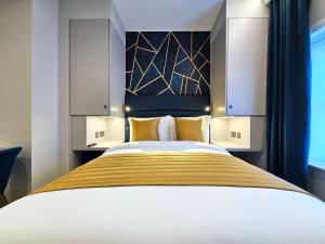 a bedroom with a large bed with a yellow blanket at NOX Paddington in London