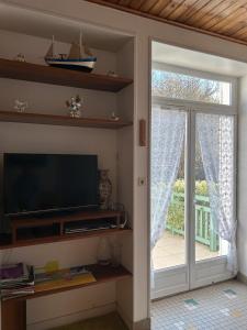 sala de estar con TV y puerta corredera de cristal en 1 - Maison de pêcheur Pré vert, en Pornic
