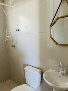Un baño con inodoro, lavabo y espejo. en Living Apartamentos 05, en Garanhuns