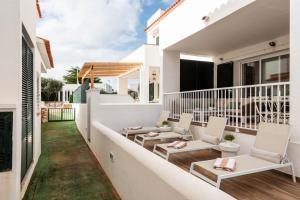 a balcony with chairs and tables on a house at 3 Bedroom Villa, 300m to Arenal d'en Castell Beach in Punta Grossa