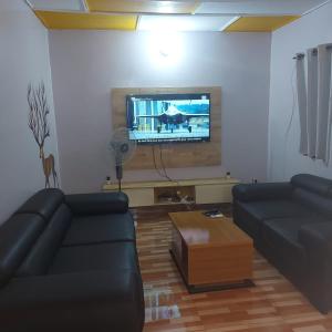 a living room with two couches and a flat screen tv at Le séjour fruité in Ouidah +3 photos